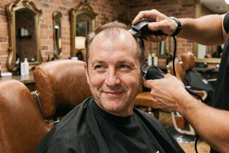 Homme aux premiers signes de calvitie recevant une coupe taper dégradée chez le coiffeur