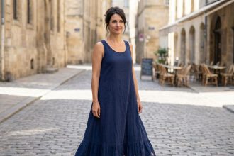 Femme épanouie portant une robe longue fluide bleu marine dans une rue pavée européenne, illustrant la confiance en soi offerte par les robes maxi
